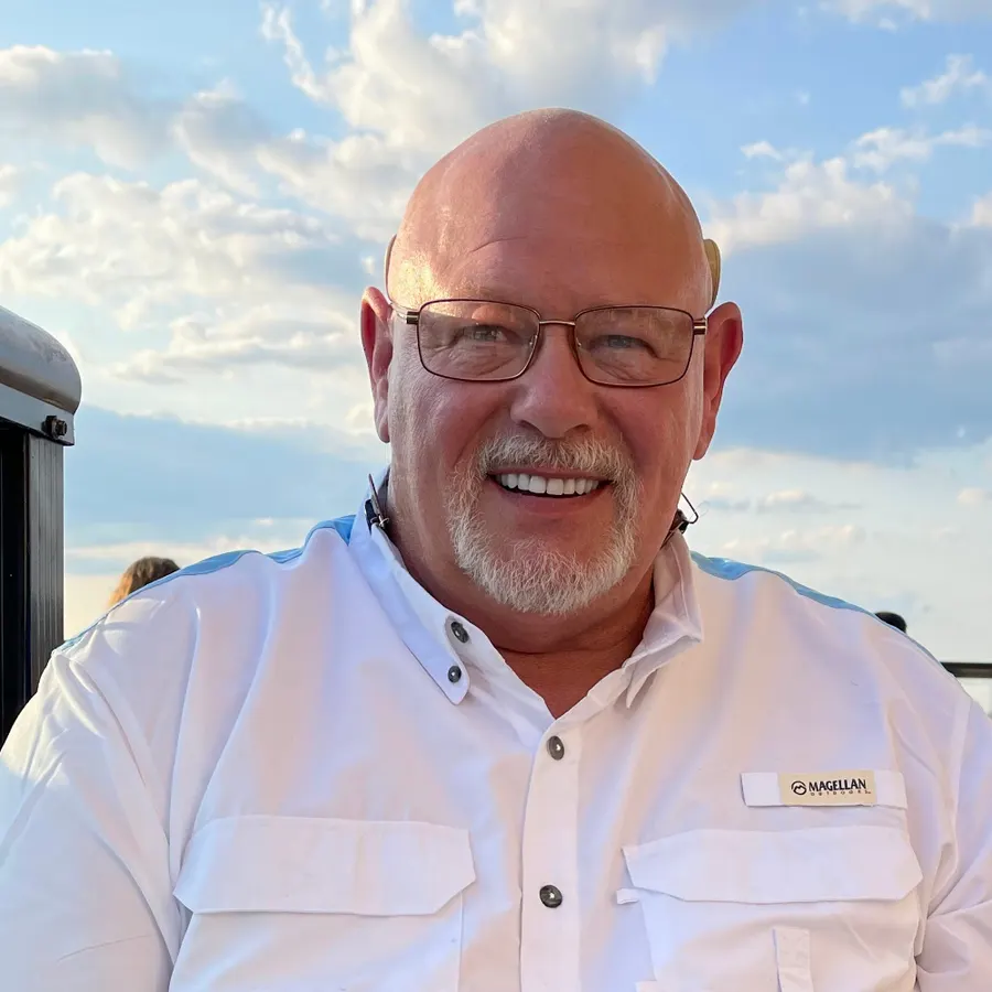 Brian Fredrick, founder of ABC Plumbing Heat and Air, smiling in a white shirt and glasses outdoors