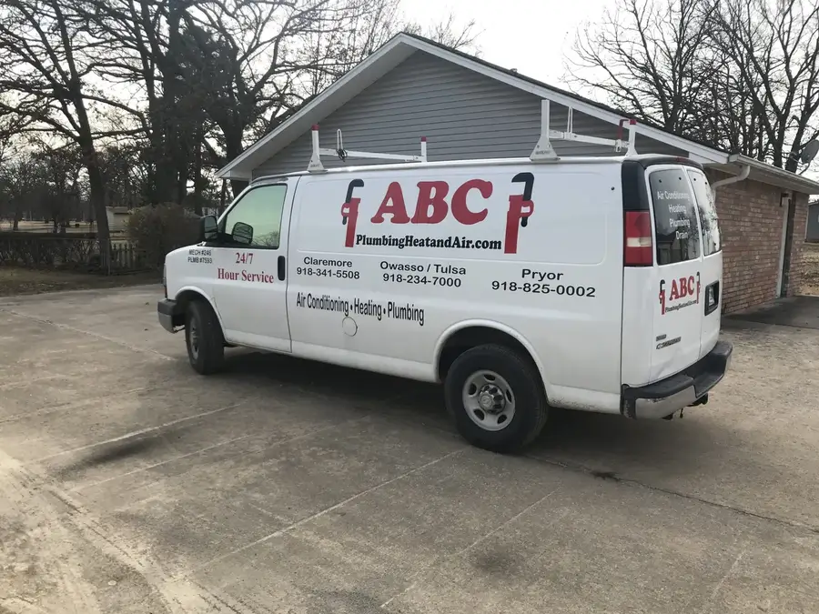 A white ABC Plumbing Heat and Air van with red lettering parked in front of a house